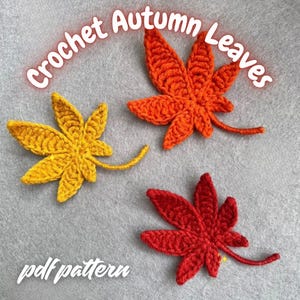 Peut inclure: Trois feuilles d'automne crochetées, jaunes, oranges et rouges, sur fond gris. Le texte "Crochet Autumn Leaves" est arqué au-dessus des feuilles, et "pdf pattern" est écrit en dessous.