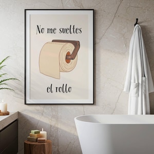 Puede incluir: Lámina enmarcada para baño con ilustración de rollo de papel higiénico en un soporte. El texto "No me sueltes el rollo" está escrito en negro. La obra se encuentra en un baño moderno con bañera blanca y albornoz.