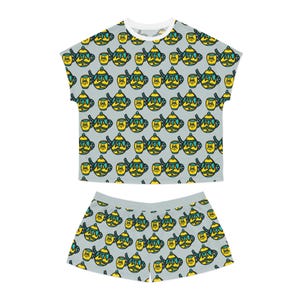 May include: A short-sleeve top and shorts set in a light grey colour featuring an all-over repeating pattern of yellow and teal cartoon teapots and matching teacups with expressive faces, black outlines, and a white crew neckline on the top.