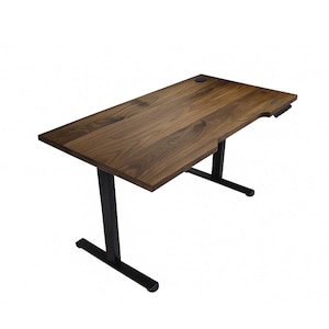 May include: A brown wooden desk with a black metal frame. The desk has a rectangular top with a cut-out on one side and a control panel. The desk is approximately 60 inches long and 30 inches wide.