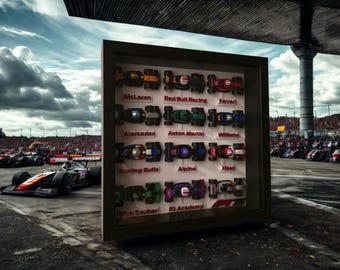 Könnte beinhalten: Eine gerahmte Vitrine mit Miniatur-Formel-1-Rennwagen, die verschiedene Teams wie McLaren, Red Bull Racing und Ferrari zeigen. Die Autos sind farbenfroh und detailliert, vor dem Hintergrund einer Rennstrecke und eines bewölkten Himmels.