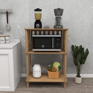 Op de afbeelding: Een licht houten keukentrolley met een blender, koffiezetapparaat en magnetron op de planken. Een witte waterkoker en een mand met groenten staan op de onderste plank. Een plant staat rechts.
