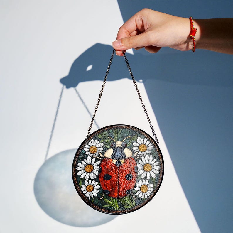 Ladybug glass suncatcher with daisy flowers glowing in sunlight, decorative spring and summer window ornament