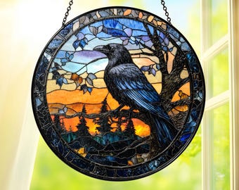 May include: A round stained glass window featuring a black raven perched on a tree branch. The artwork depicts a sunset scene with orange, blue, and green hues. The window is framed with a dark border and hangs from a chain.