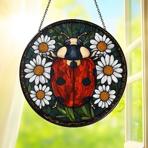 May include: Round stained glass window art featuring a red ladybug with black spots, surrounded by white daisies with yellow centers. The ladybug is centered on a dark green background. The artwork is framed in a dark brown border and hangs from a chain.