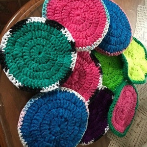 May include: A collection of crocheted coasters in various colors, including pink, green, blue, and purple. The coasters are circular and have a textured, crocheted design.