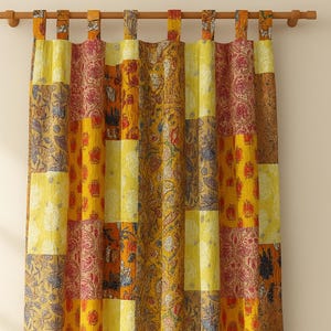 Puede incluir: Cortina de patchwork con una variedad de patrones y colores, incluyendo amarillo, naranja y burdeos. La cortina de tela tiene un bolsillo para la barra en la parte superior para colgar. El diseño incluye motivos florales y paisley.