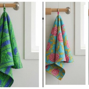 K&ouml;nnte beinhalten: Eine Sammlung von f&uuml;nf dekorativen K&uuml;chent&uuml;chern, die an einer Holzstange h&auml;ngen. Die T&uuml;cher weisen verschiedene farbenfrohe Blumen- und geometrische Muster in Rosa, Gr&uuml;n, Blau, Schwarz und Rot auf. Jedes Tuch ist etwa 50 cm lang.