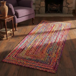 May include: A rectangular, multi-colored braided rug with a vibrant mix of red, orange, yellow, green, and blue hues. The rug features a bordered design and is placed on a wooden floor, adding a pop of color to the room.
