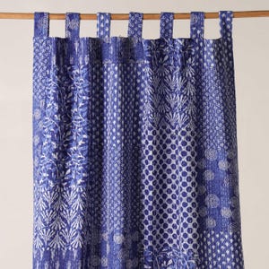 Könnte beinhalten: Blau-weiß gemusterter Vorhang mit verschiedenen Designs, darunter Punkte, Wirbel und Blattmuster. Der Vorhang hängt an einer Holzstange mit Stoffschlaufen.