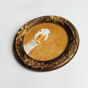 Unique animal illustration featuring a white goose, painted by hand and mounted in an ornate antique bronze resin frame.