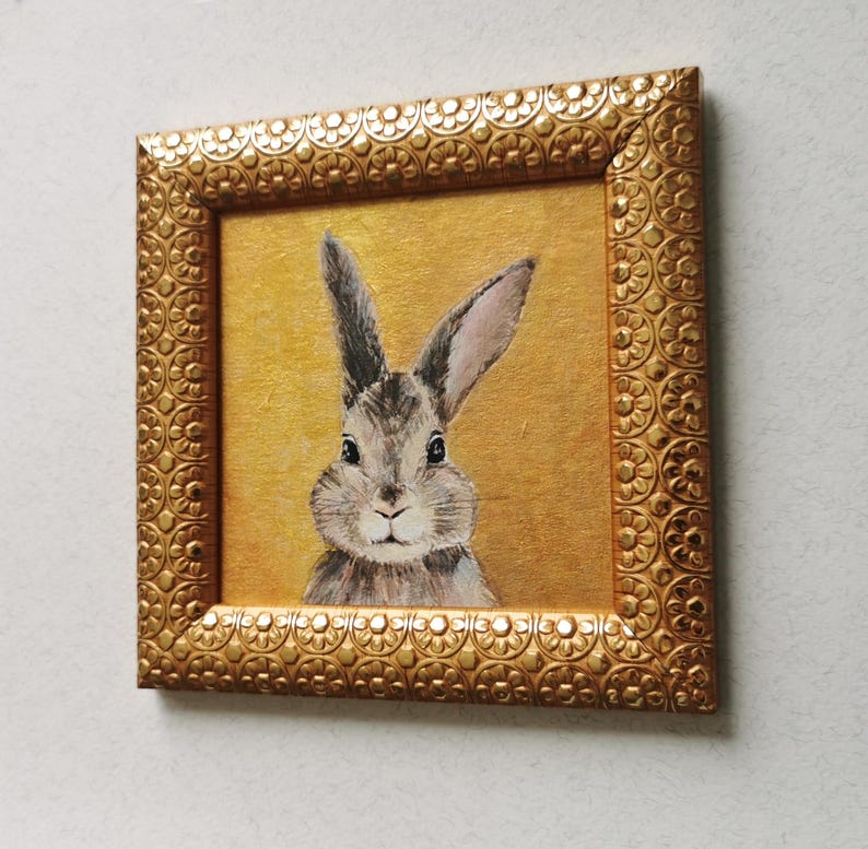 Close-up of hand-painted rabbit face on gold-textured canvas.