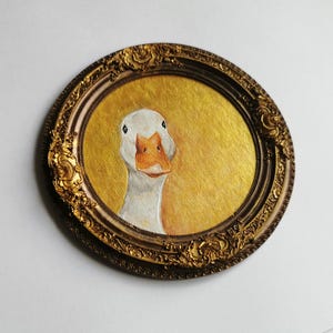 Miniature goose wall art painted on cardboard and fixed inside a non removable bronze resin frame with a back loop for hanging.