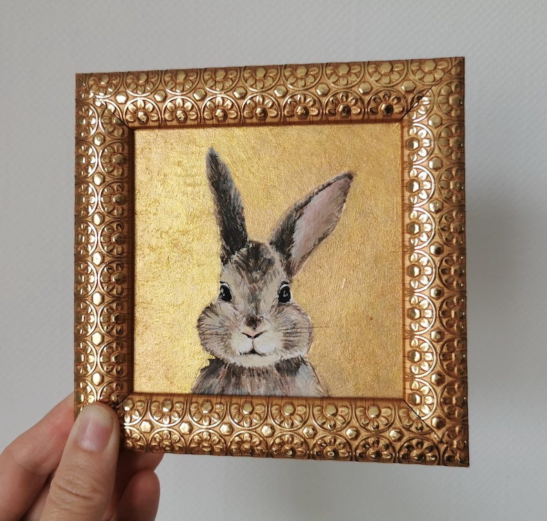 Bunny acrylic painting with vintage-style frame on neutral wall.