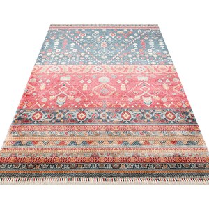 K&ouml;nnte beinhalten: Ein rechteckiger Teppich mit einem detaillierten, geometrischen Muster. Der Teppich hat eine Farbpalette aus Blau, Rot und Orange mit einem Fransenrand. Das Design umfasst verschiedene Formen und Motive, die ein strukturiertes Aussehen erzeugen.