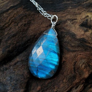 May include: A silver chain necklace with a teardrop-shaped blue labradorite gemstone pendant.