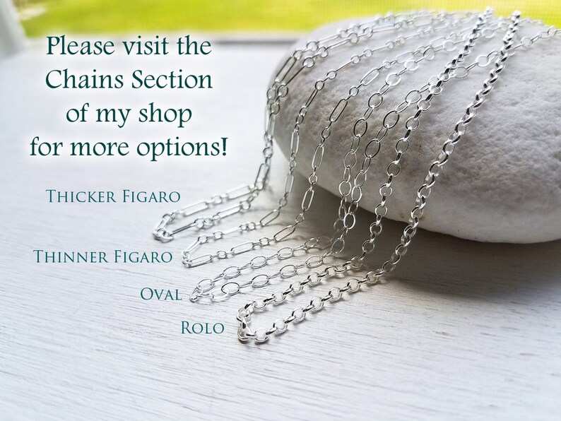 Puede incluir: Cinco tipos diferentes de cadenas de plata sobre una roca blanca. Las cadenas est&aacute;n etiquetadas como "Thicker Figaro", "Thinner Figaro", "Oval" y "Rolo".