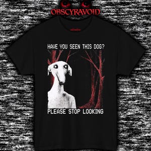 Puede incluir: Camiseta negra con una ilustración blanca de una criatura parecida a un perro y el texto "HAVE YOU SEEN THIS DOG? PLEASE STOP LOOKING." El diseño incluye formas rojas en forma de árbol en el fondo. La marca "OBSCYRAVOID" está en la parte superior.