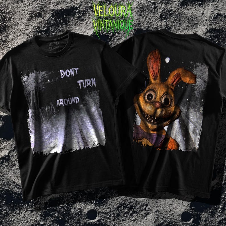 This analog horror-inspired T-shirt features the phrase “DON’T TURN AROUND” printed across a dark, eerie forest road under moonlight. On the other side, a creepy, distorted bunny character stares with a wide unsettling grin. The design blends glitchcore, VHS static, and nightmare-style textures for a perfect horror aesthetic. Printed on soft, high-quality fabric, ideal for horror fans and lovers of dark surreal art.