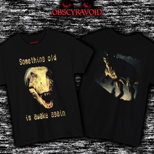 This analog horror–inspired T-shirt features a terrifying decayed dinosaur with human-like eyes and sharp teeth under the phrase “Something old is awake again.” The design combines VHS-style grain, eerie lighting, and vintage texture to create a haunting prehistoric horror vibe. Perfect for analog horror fans, dinosaur lovers, and retro-style collectors. Printed on high-quality fabric for lasting comfort and style.
