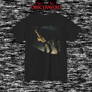 This analog horror–inspired T-shirt features a terrifying decayed dinosaur with human-like eyes and sharp teeth under the phrase “Something old is awake again.” The design combines VHS-style grain, eerie lighting, and vintage texture to create a haunting prehistoric horror vibe. Perfect for analog horror fans, dinosaur lovers, and retro-style collectors. Printed on high-quality fabric for lasting comfort and style.