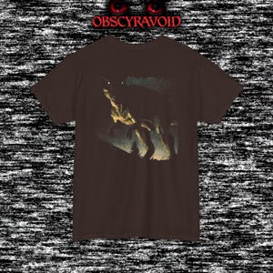 This analog horror–inspired T-shirt features a terrifying decayed dinosaur with human-like eyes and sharp teeth under the phrase “Something old is awake again.” The design combines VHS-style grain, eerie lighting, and vintage texture to create a haunting prehistoric horror vibe. Perfect for analog horror fans, dinosaur lovers, and retro-style collectors. Printed on high-quality fabric for lasting comfort and style.