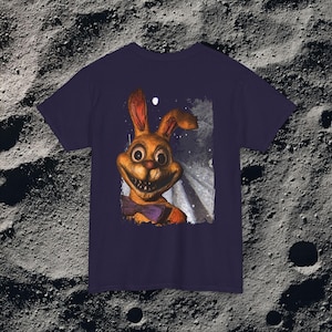 This analog horror-inspired T-shirt features the phrase “DON’T TURN AROUND” printed across a dark, eerie forest road under moonlight. On the other side, a creepy, distorted bunny character stares with a wide unsettling grin. The design blends glitchcore, VHS static, and nightmare-style textures for a perfect horror aesthetic. Printed on soft, high-quality fabric, ideal for horror fans and lovers of dark surreal art.