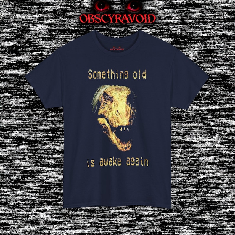 This analog horror–inspired T-shirt features a terrifying decayed dinosaur with human-like eyes and sharp teeth under the phrase “Something old is awake again.” The design combines VHS-style grain, eerie lighting, and vintage texture to create a haunting prehistoric horror vibe. Perfect for analog horror fans, dinosaur lovers, and retro-style collectors. Printed on high-quality fabric for lasting comfort and style.