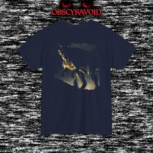 This analog horror–inspired T-shirt features a terrifying decayed dinosaur with human-like eyes and sharp teeth under the phrase “Something old is awake again.” The design combines VHS-style grain, eerie lighting, and vintage texture to create a haunting prehistoric horror vibe. Perfect for analog horror fans, dinosaur lovers, and retro-style collectors. Printed on high-quality fabric for lasting comfort and style.