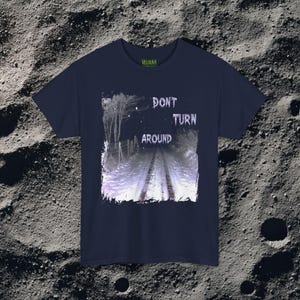 This analog horror-inspired T-shirt features the phrase “DON’T TURN AROUND” printed across a dark, eerie forest road under moonlight. On the other side, a creepy, distorted bunny character stares with a wide unsettling grin. The design blends glitchcore, VHS static, and nightmare-style textures for a perfect horror aesthetic. Printed on soft, high-quality fabric, ideal for horror fans and lovers of dark surreal art.