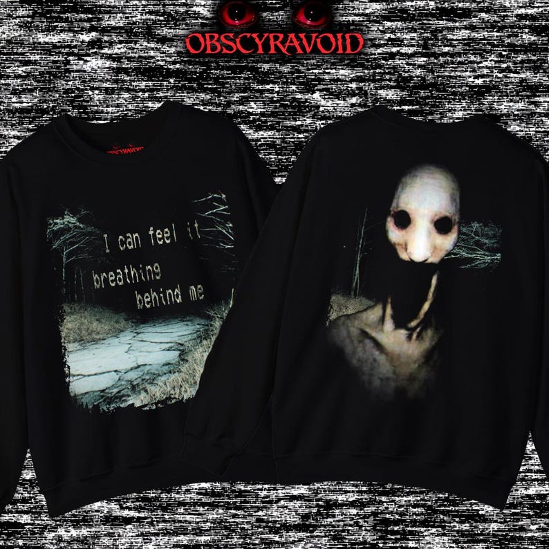 This analog horror sweatshirt features a chilling dual-sided design. The front shows a dark, grainy forest scene with glitchy text reading “I can feel it breathing behind me.” The back displays a disturbing pale creature emerging from the shadows, created with VHS static, noise, and eerie textures. Perfect for horror fans who love unsettling artwork, dark aesthetics, creepy forest themes, and lost-footage style designs.
