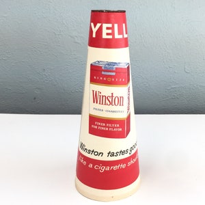 May include: Vintage Winston cigarettes cone-shaped cardboard display. The display is red and white with the text "YELL", "KING SIZE", "Winston", "FILTER-CIGARETTES", "FINER FILTER FOR FINER FLAVOR", and "Winston tastes good like a cigarette should".