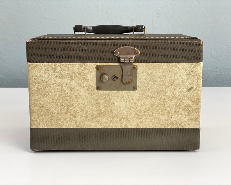 May include: A vintage brown and cream suitcase with a metal latch and a black handle.