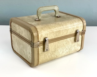 May include: A vintage off-white travel case with a brown trim and silver hardware. The case has a handle on the top and a textured surface.