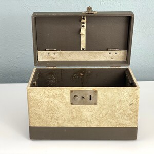 May include: A vintage, brown and beige, lockable storage box with a metal latch and keyhole. The box is open and the inside is empty.