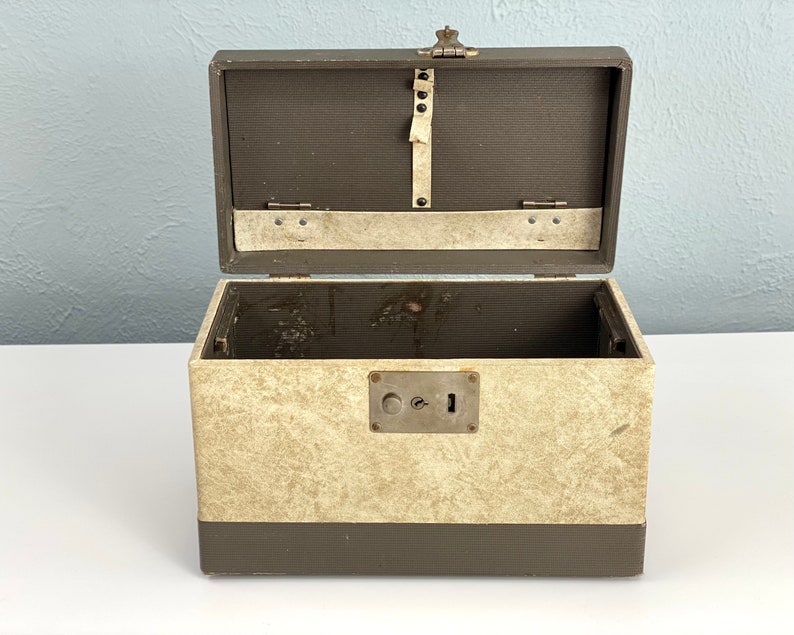 May include: A vintage, brown and beige, lockable storage box with a metal latch and keyhole. The box is open and the inside is empty.