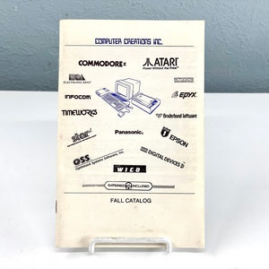 以下が含まれることがあります： コンピューター・クリエイションズ社の白黒のカタログの表紙。コモドール、アタリ、インフォコム、タイムワークス、スター、パナソニック、エピックス、ブロダーバンド・ソフトウェア、OSS、ウィコ、エプソン、デジタル・デバイスのロゴが掲載されている。ページの下部には「FALL CATALOG」の文字が印刷されている。