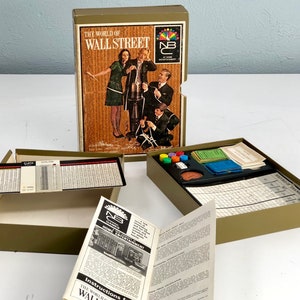 May include: A vintage board game called "The World of Wall Street" by NBC Home Entertainment. The box features a photo of people playing the game. The game board is open and shows the game pieces and cards.