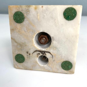 May include: The bottom of a white marble sculpture base with four green felt pads and two metal screws.