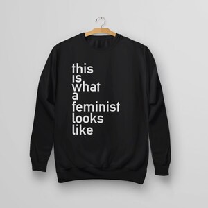 Pu&ograve; includere: Felpa nera con testo bianco che dice "this is what a feminist looks like".