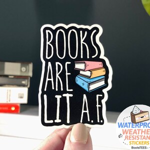 May include: A black and white sticker with the text "BOOKS ARE LIT A.F." and a stack of colorful books. The sticker is waterproof and weather resistant.