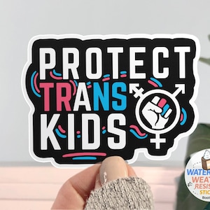 May include: Black and white sticker with the text "PROTECT TRANS KIDS" in pink, blue, and white. The sticker features a fist with a transgender symbol in the center.