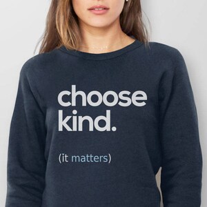 以下が含まれることがあります： 白い文字で「choose kind. (it matters)」と書かれた紺色のスウェットシャツです。