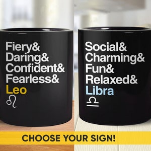 May include: Two black coffee mugs with white text and astrological symbols. The mug on the left says "Fiery & Daring & Confident & Fearless & Leo" with the Leo symbol. The mug on the right says "Social & Charming & Fun & Relaxed & Libra" with the Libra symbol. The text "CHOOSE YOUR SIGN!" is below the mugs.