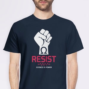 Pode incluir: Uma camiseta azul marinho com um punho branco levantado no ar. O punho segura um s&iacute;mbolo &ocirc;mega. O texto "RESIST" est&aacute; em letras vermelhas abaixo do punho. Abaixo do texto h&aacute; uma linha ondulada e o texto "SCIENCE IS POWER".