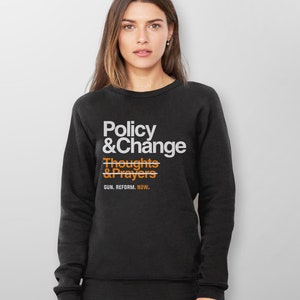 May include: Black sweatshirt with white text that reads "Policy & Change" with a line through "Thoughts & Prayers" and the text "GUN. REFORM. NOW." below.