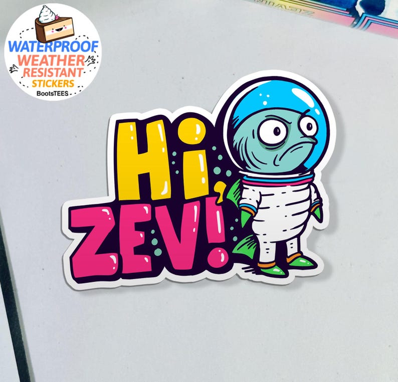 May include: A sticker featuring a cartoon alien astronaut with a blue helmet and a grumpy expression. The sticker says "Hi Zev!" in yellow and pink bubble letters. The sticker is waterproof and weather resistant.