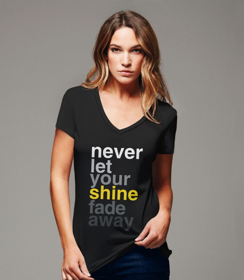 May include: Black V-neck t-shirt with the text "never let your shine fade away" printed in white and yellow.