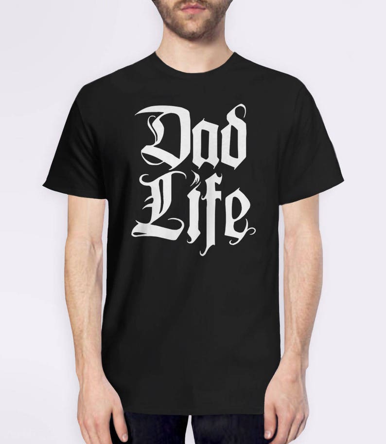 Puede incluir: Camiseta negra con texto blanco que dice "Dad Life" en una fuente estilizada.