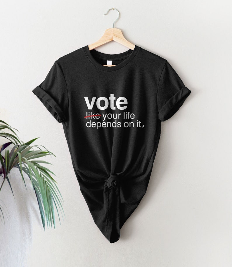 May include: Black t-shirt with white text that reads "vote like your life depends on it."
